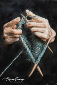 Porcelain artwork titled "My Mother's Embrace", showing two hands weaving wool using oil on a black background by Marina Fiamingo.